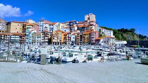 A marina with numerous boats docked, surrounded by colorful buildings with red-tiled roofs. - Aldatzeta Ostatua (Bermeo)