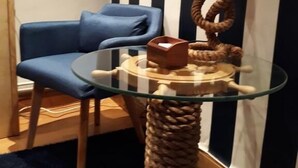 A room with a glass-top table, a blue chair, a rope cat tree, and striped wallpaper. - Aldatzeta Ostatua (Bermeo)