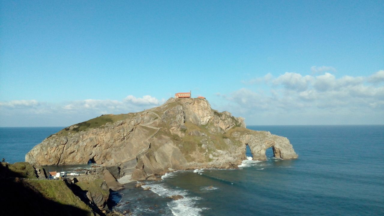 A rocky island with a small building on top, surrounded by water.