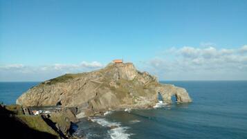 A rocky island with a small building on top, surrounded by water.
