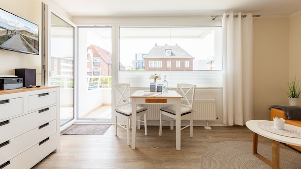 Un salon moderne comprenant une table à manger, des chaises, un canapé et un téléviseur posé sur un meuble.