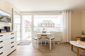 A modern living room with a dining table, chairs, a sofa, and a TV on a cabinet. - Tüti in the Sola Bona house (Westerland)