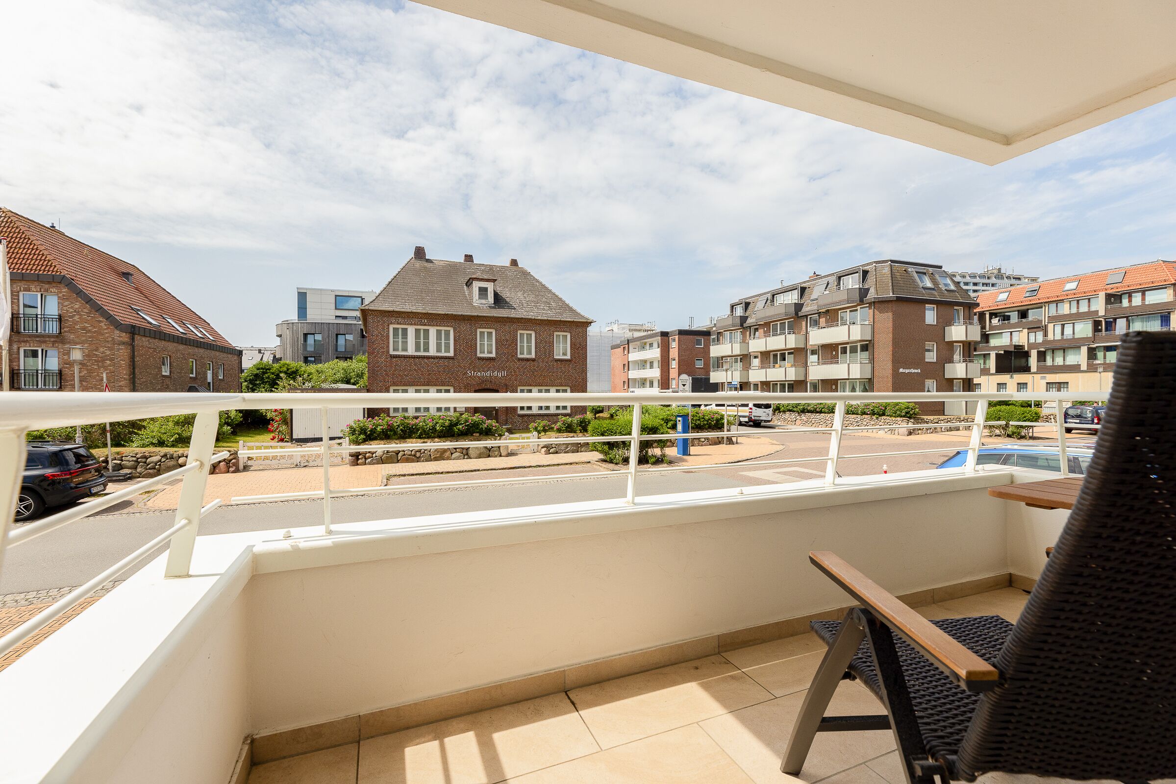 Un balcone con vista su una zona residenziale, che include una casa con il cartello "Stadthaus" e un edificio moderno.