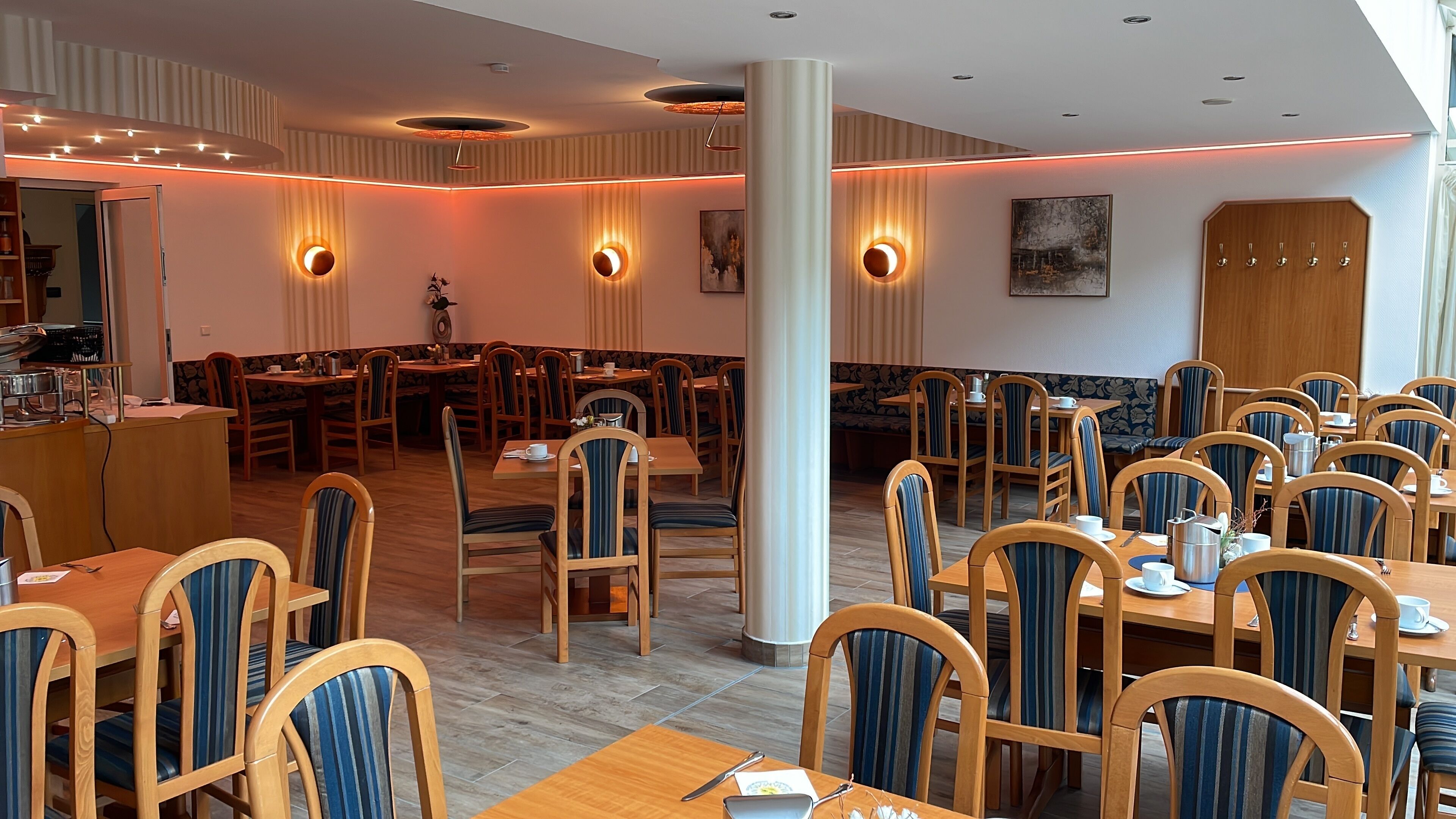 A spacious restaurant with wooden tables and chairs, ambient lighting, and a modern interior design.