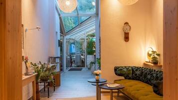 A cozy interior with a wooden floor, a green sofa, a small table, and a wall clock.