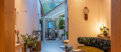 A cozy interior with a wooden floor, a green sofa, a small table, and a wall clock.