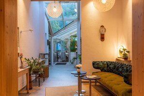 Ein gemütliches Interieur mit Holzboden, einem grünen Sofa, einem kleinen Tisch und einer Wanduhr.