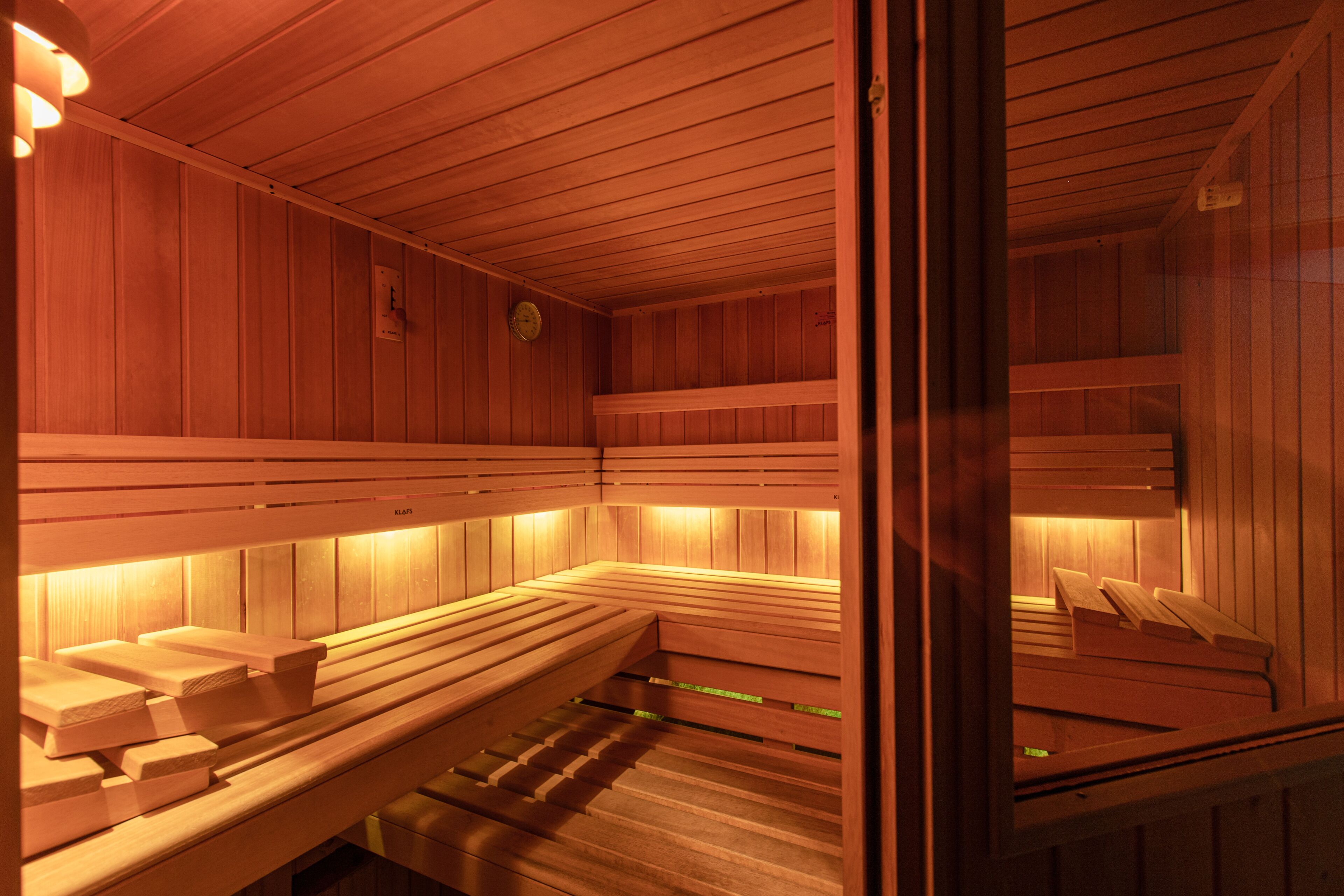 A sauna with wooden benches and benches, a wooden ceiling, and a visible wall clock.