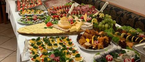 A buffet table with various food items including salads, cheeses, meats, and seafood.
