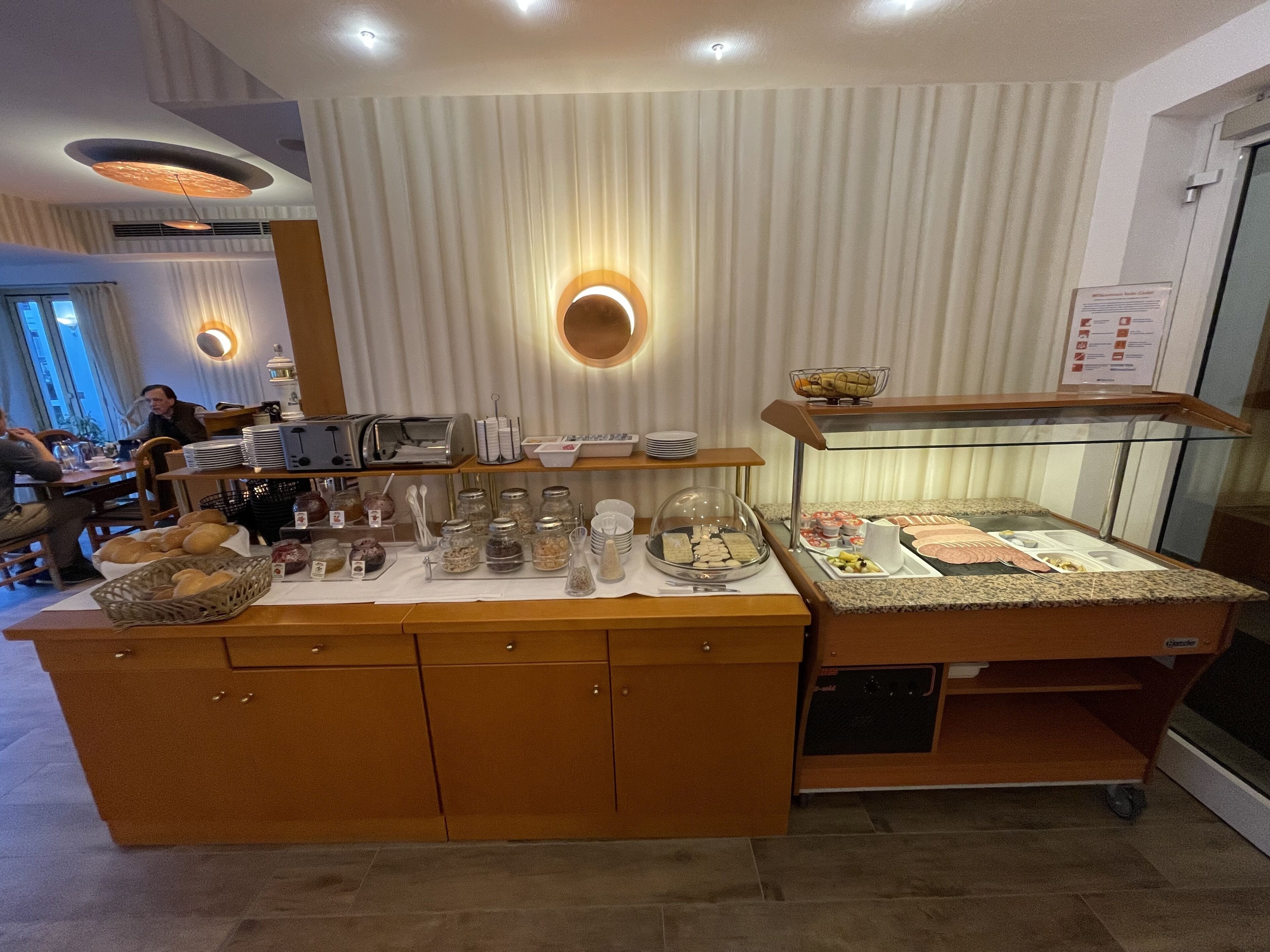 A buffet setup with various food items, a coffee station, and a seating area with tables and chairs.