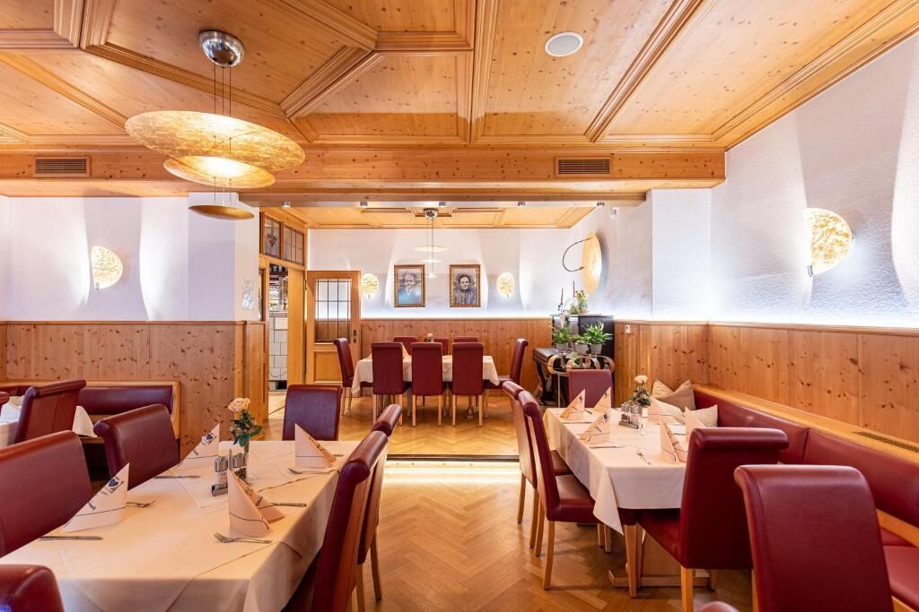 A restaurant with wooden paneling, red upholstered booths, and white tablecloths.