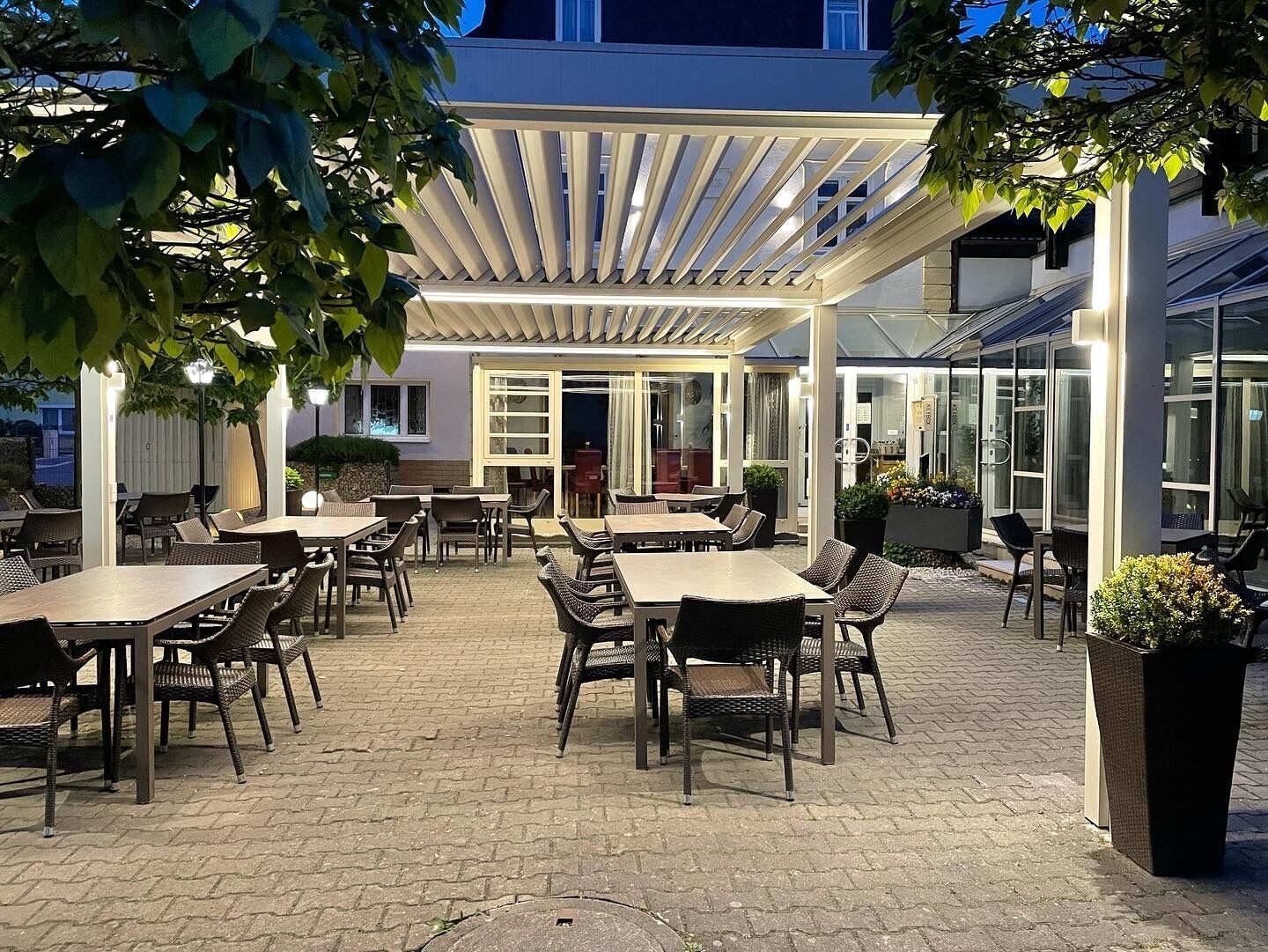 An outdoor patio area with tables and chairs, a covered seating area, and a glass door entrance.