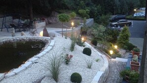 A landscaped garden with a pond, seating area, and potted plants.