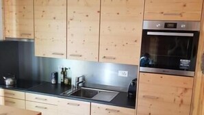 Eine moderne Küche mit Holzausstattung, einer Edelstahl-Spüle und einem eingebauten Backofen.