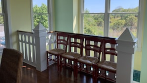 Ein Zimmer mit einer Holzbank, großen Fenstern und Blick auf Grünfläche.