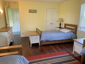 Ein Schlafzimmer mit einem Holzbett, einem Nachttisch, einer Kommode und einer Tür.