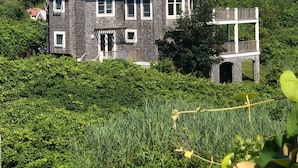 Ein zweistöckiges Haus mit Satteldach, einer Veranda und einem Balkon im zweiten Stock.