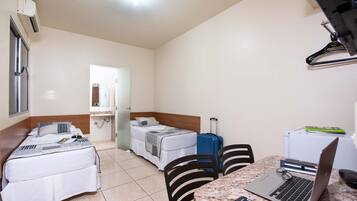 Habitación de hotel con dos camas, un escritorio, una computadora portátil, una maleta y un control remoto.