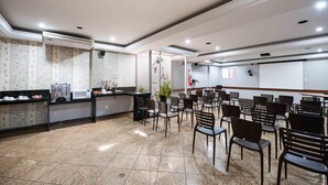 Un vestíbulo de hotel con una recepción, sillas dispuestas para los huéspedes, un extintor y un ventanal grande.