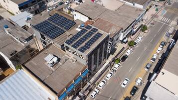 A hotel with multiple floors, solar panels on the roof, and a street with cars.