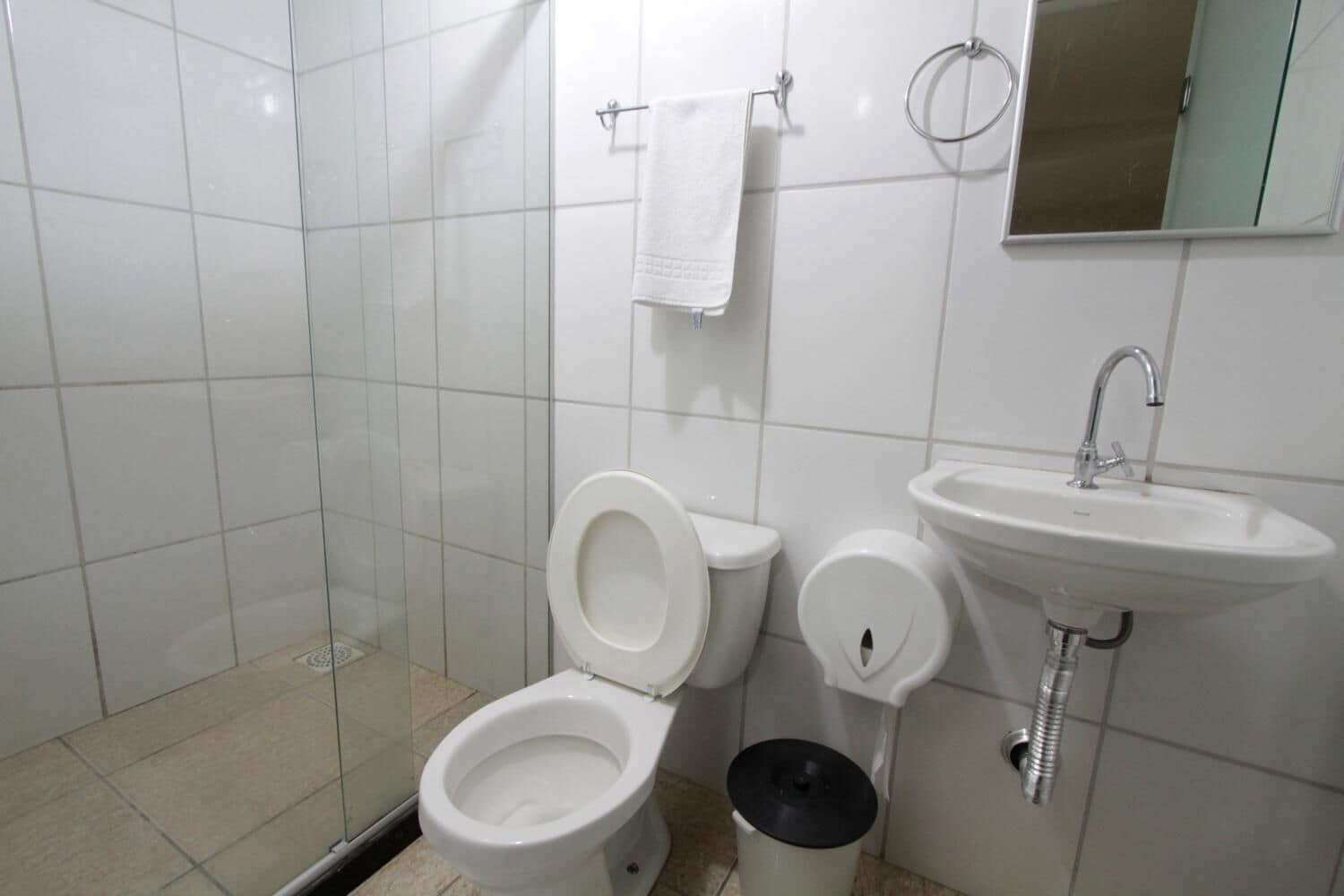 A bathroom with a toilet, bidet, sink, and a glass shower enclosure.
