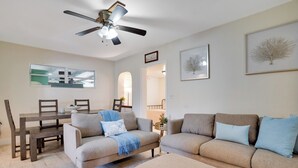 Una sala de estar con ventilador de techo, una mesa de comedor con sillas, un sofá y una mesa de centro.