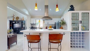 A modern kitchen with a central island, pendant lights, and a built-in oven.