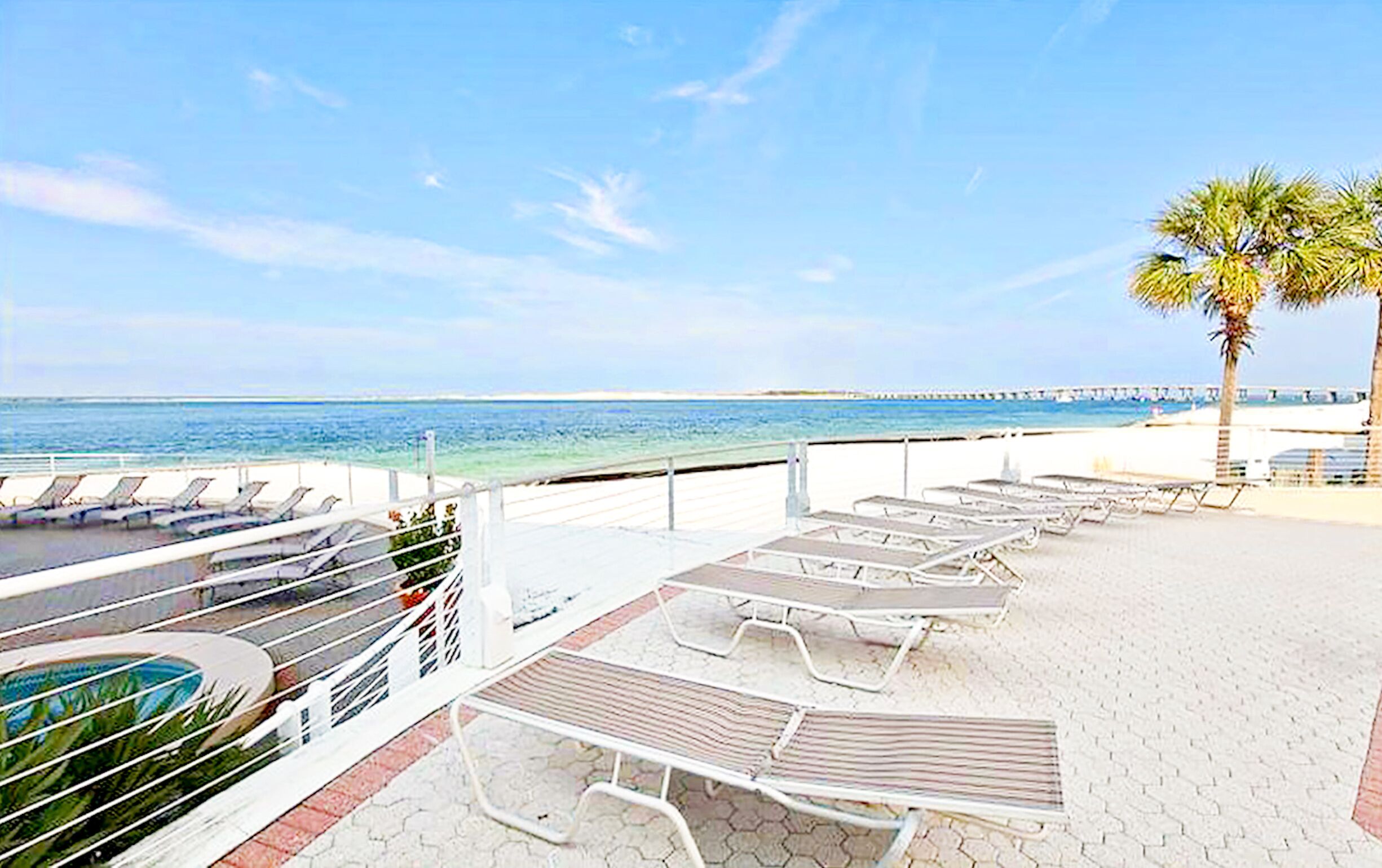 Zona de platja amb gandules i una piscina, amb vista al mar i un moll.