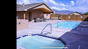 Uma área de piscina com hidromassagem, espreguiçadeiras e vista para as montanhas.