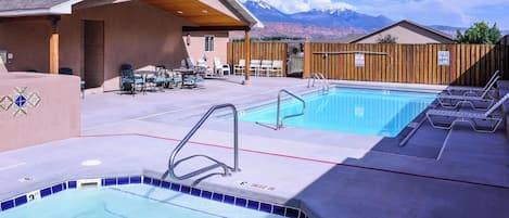Un espace piscine doté d’un jacuzzi, de chaises longues et offrant une vue sur les montagnes.
