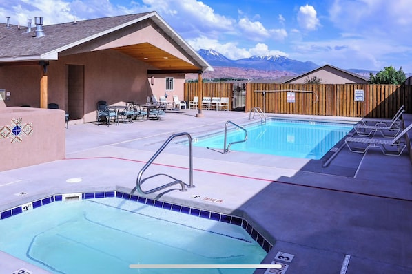 A pool area with a hot tub, lounge chairs, and a view of mountains. - Modern Moab Villa, Sleeps 7, WIFI, BBQ (Moab)