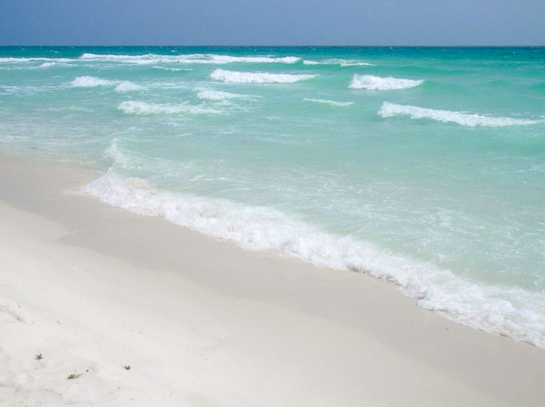 A beach with clear turquoise water and white sand.
