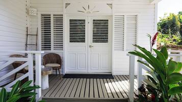 A white wooden porch with a door, a small table, and a chair.