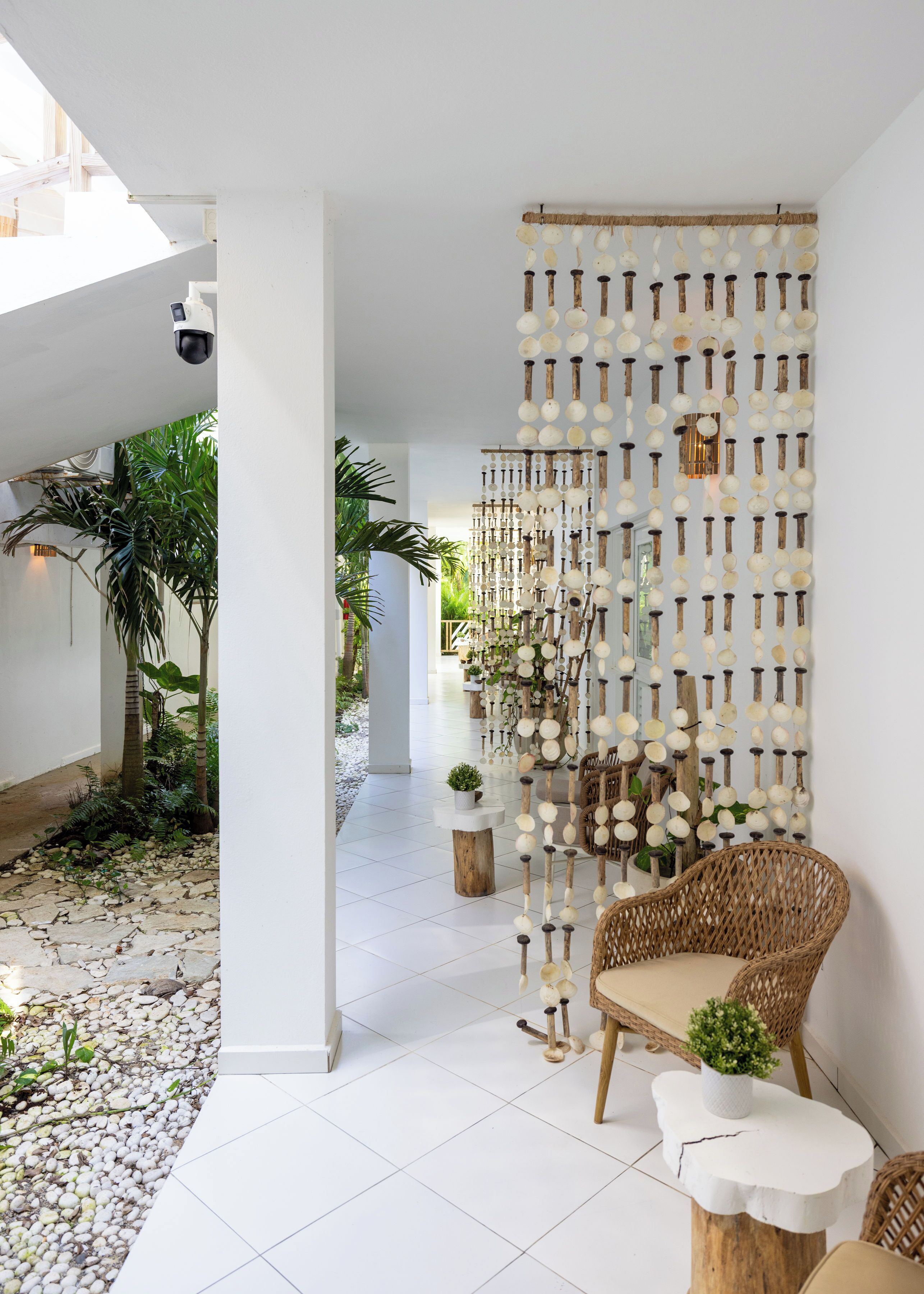 Un intérieur moderne avec un fauteuil en osier, une table blanche et un mur décoratif orné d’objets sphériques.