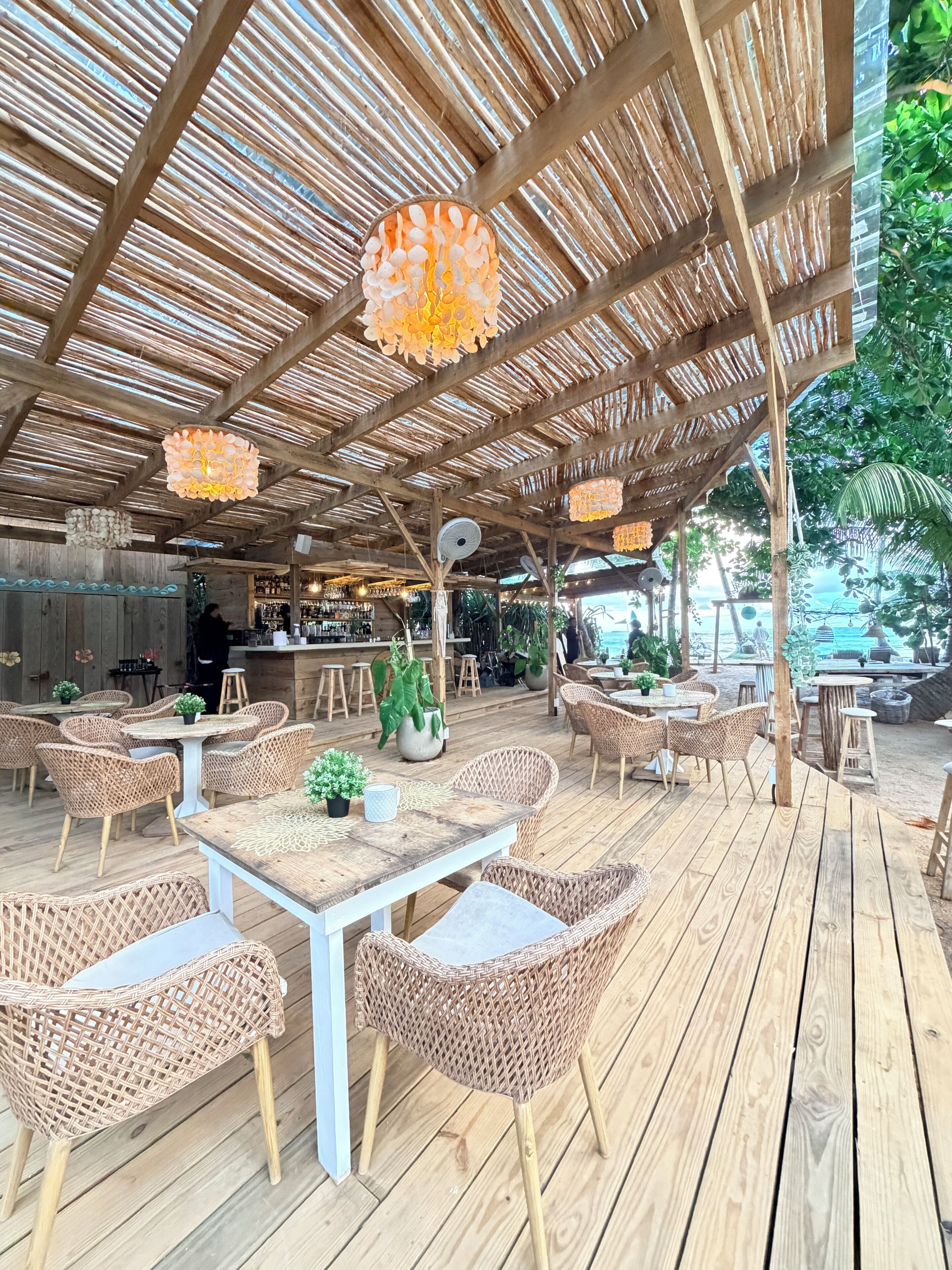 An outdoor seating area with wicker furniture, a bar, and a thatched roof.