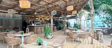 An outdoor seating area with wicker furniture, a bar, and a thatched roof.