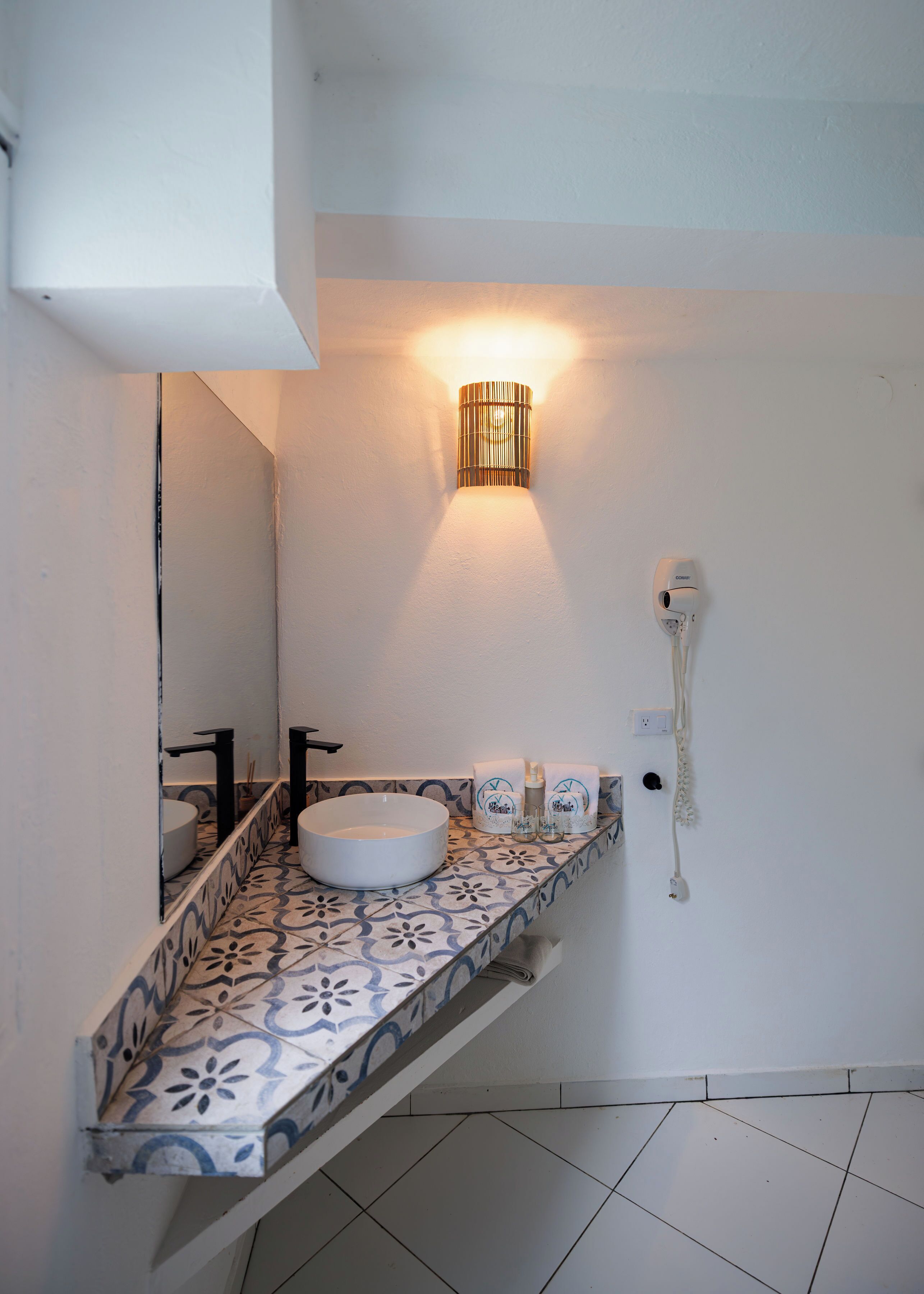 A bathroom with a white sink, a mirror, a wall-mounted light, and a telephone.