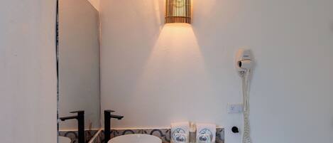 A bathroom with a white sink, a mirror, a wall-mounted light, and a telephone.