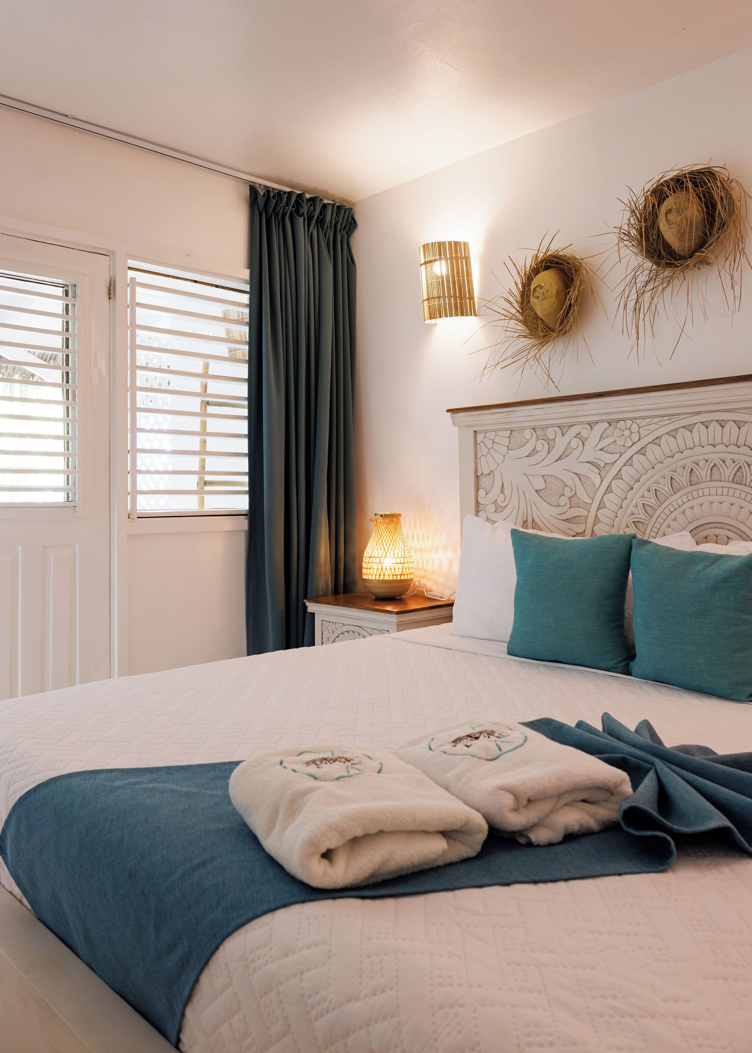 A bedroom with a bed, a nightstand, a lamp, and a window with curtains.