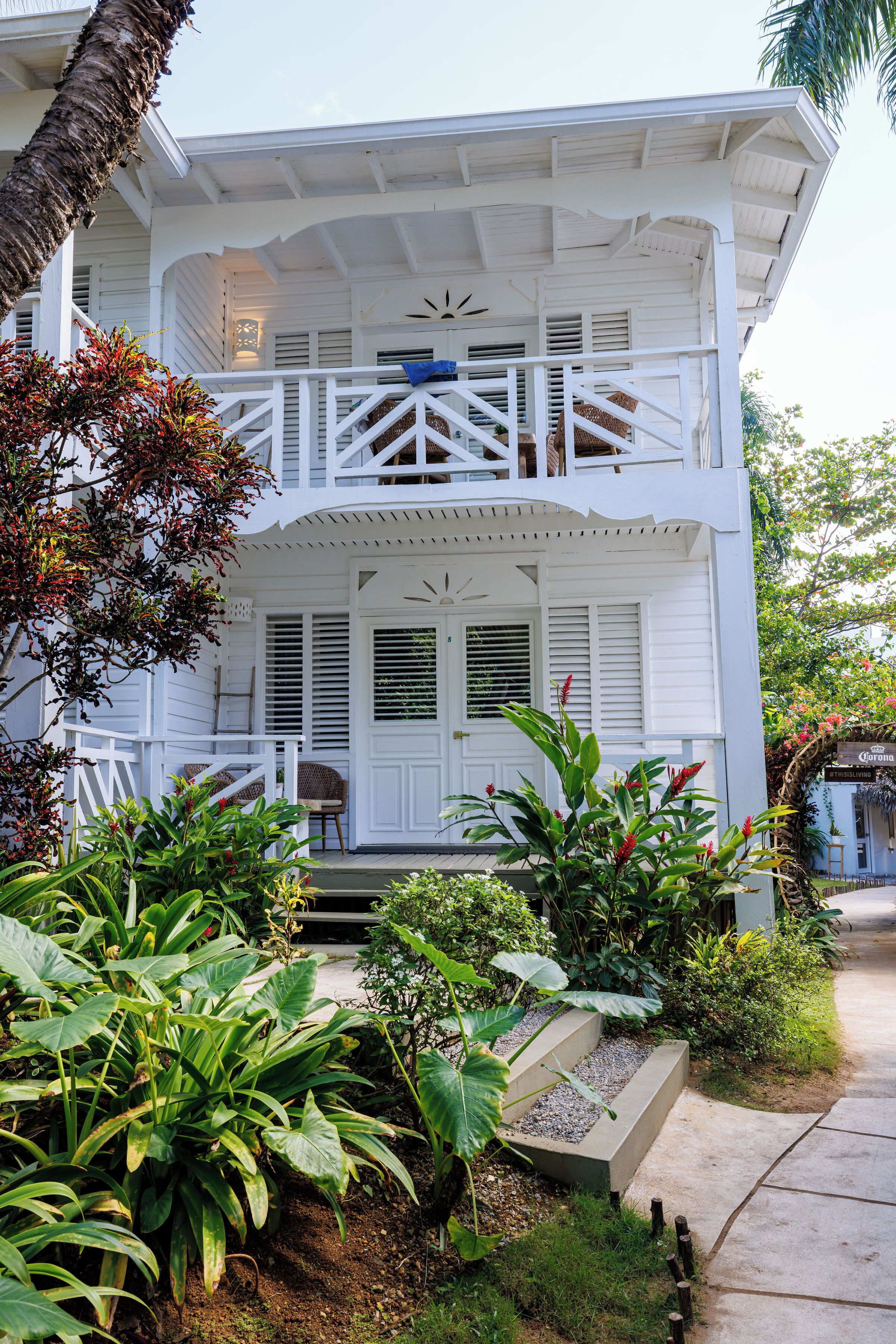 A two-story house with a porch, a fan, and a small garden area.