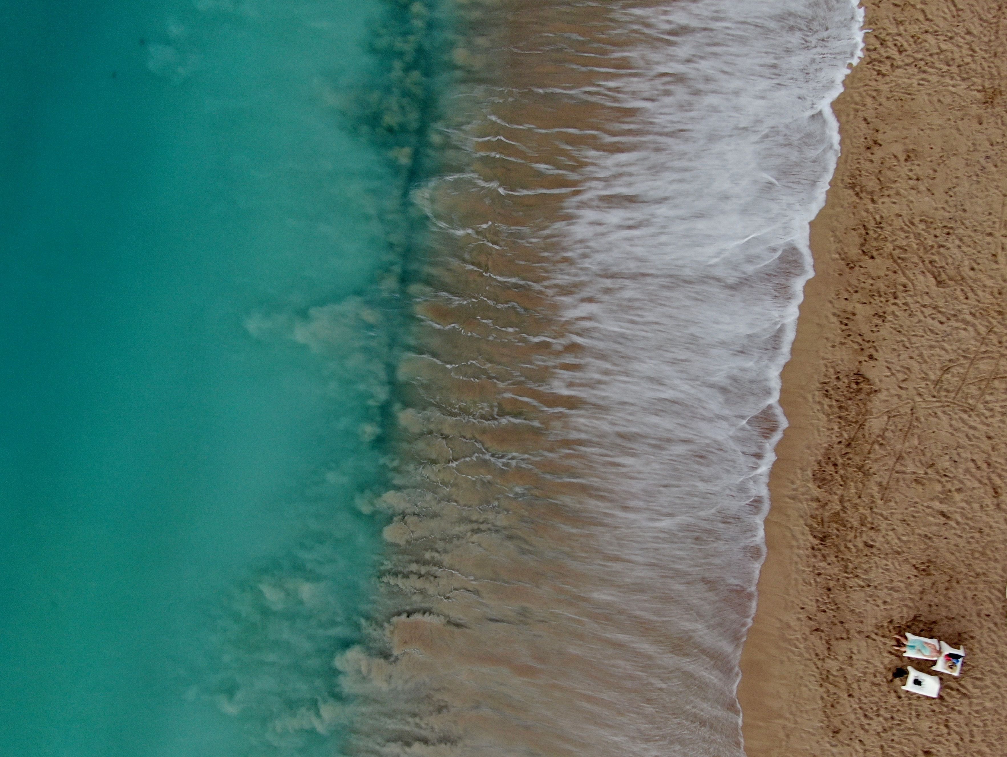 An aerial view of a beach with a few beach chairs and umbrellas.
