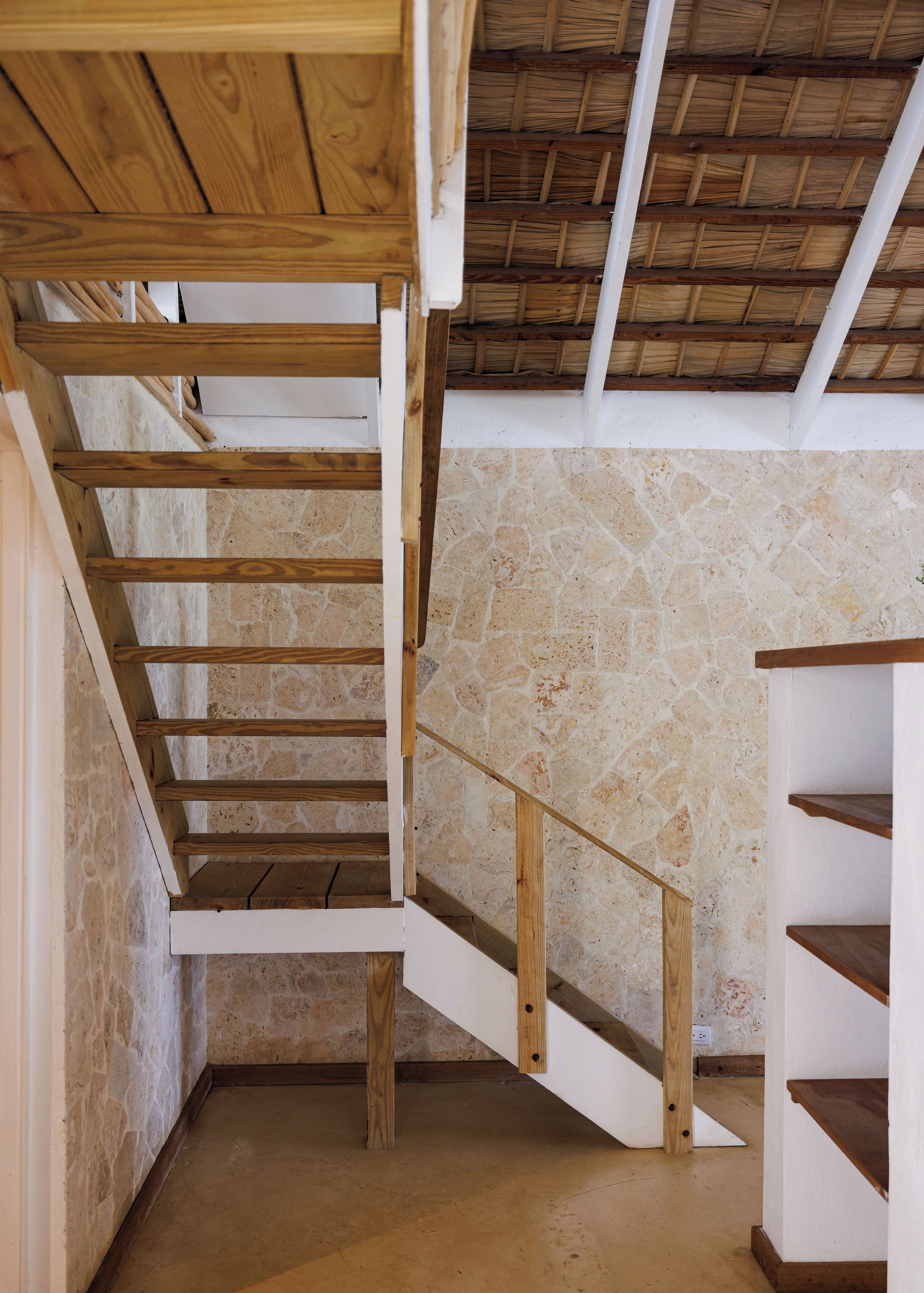 A wooden staircase with stone walls and a thatched roof.