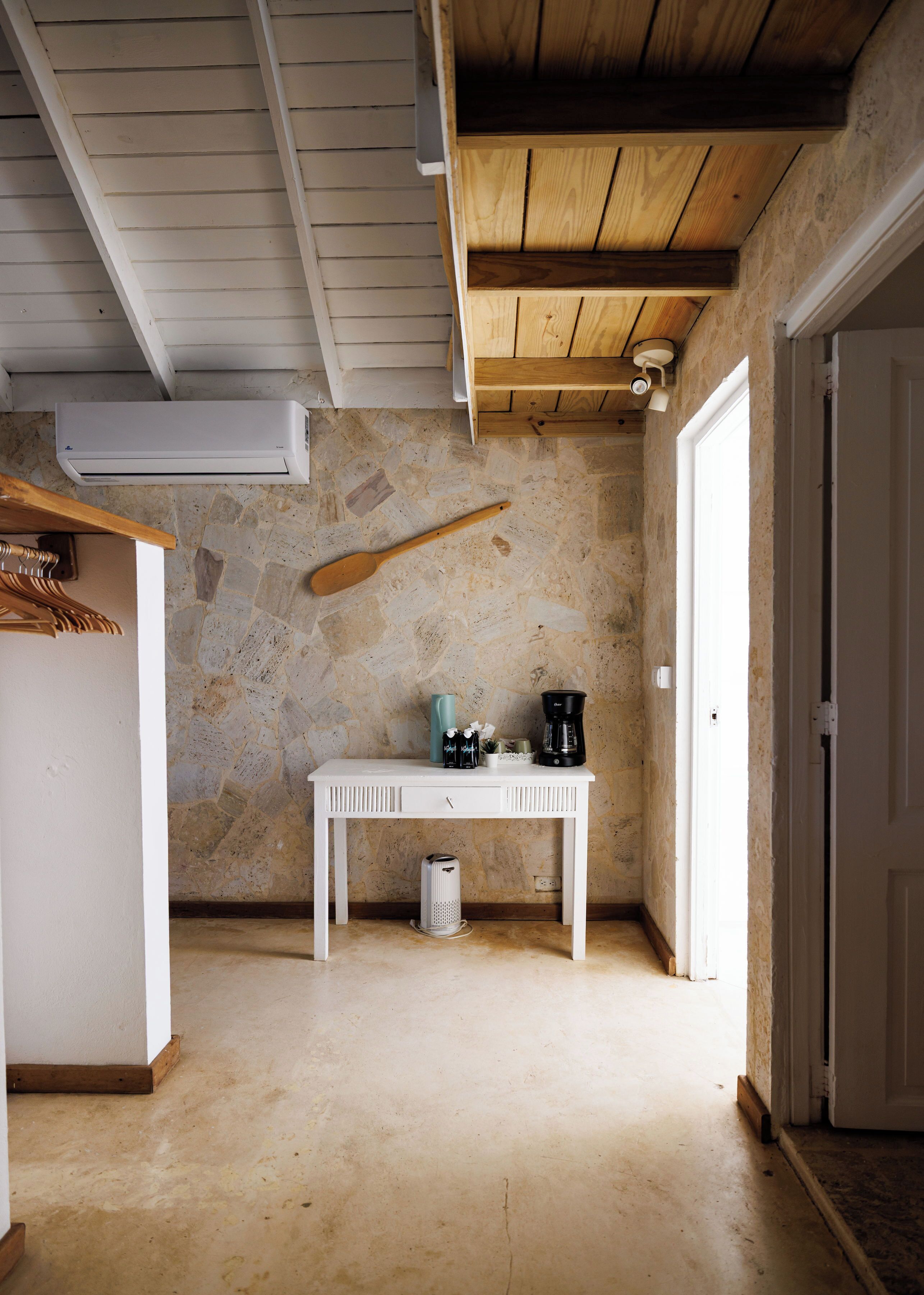 Ein Zimmer mit einem weißen Tisch, einer Steinsäule und einer Holzbalkendecke.