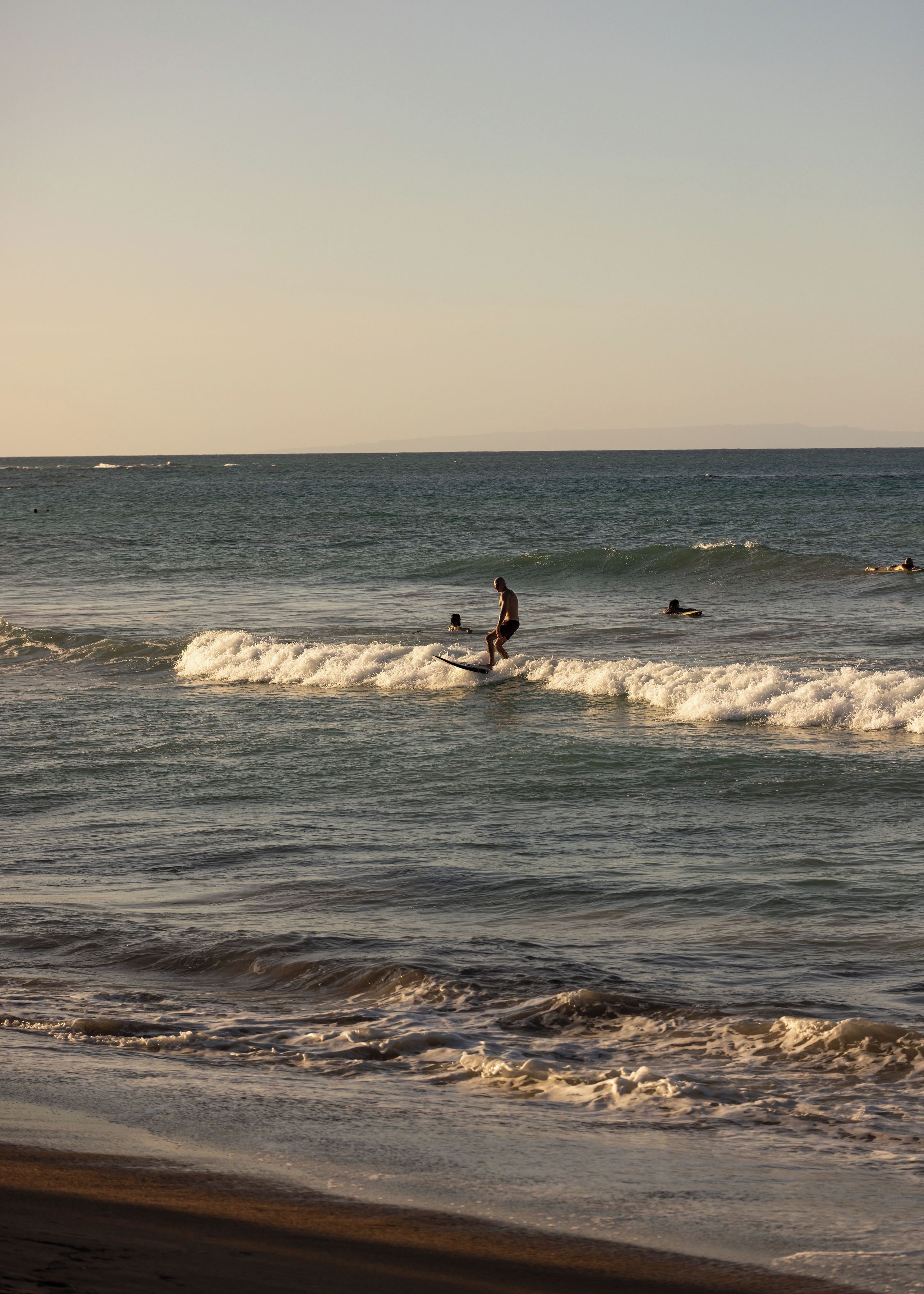Escena de playa con olas y gente practicando surf.