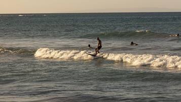 Escena de playa con olas y gente practicando surf.