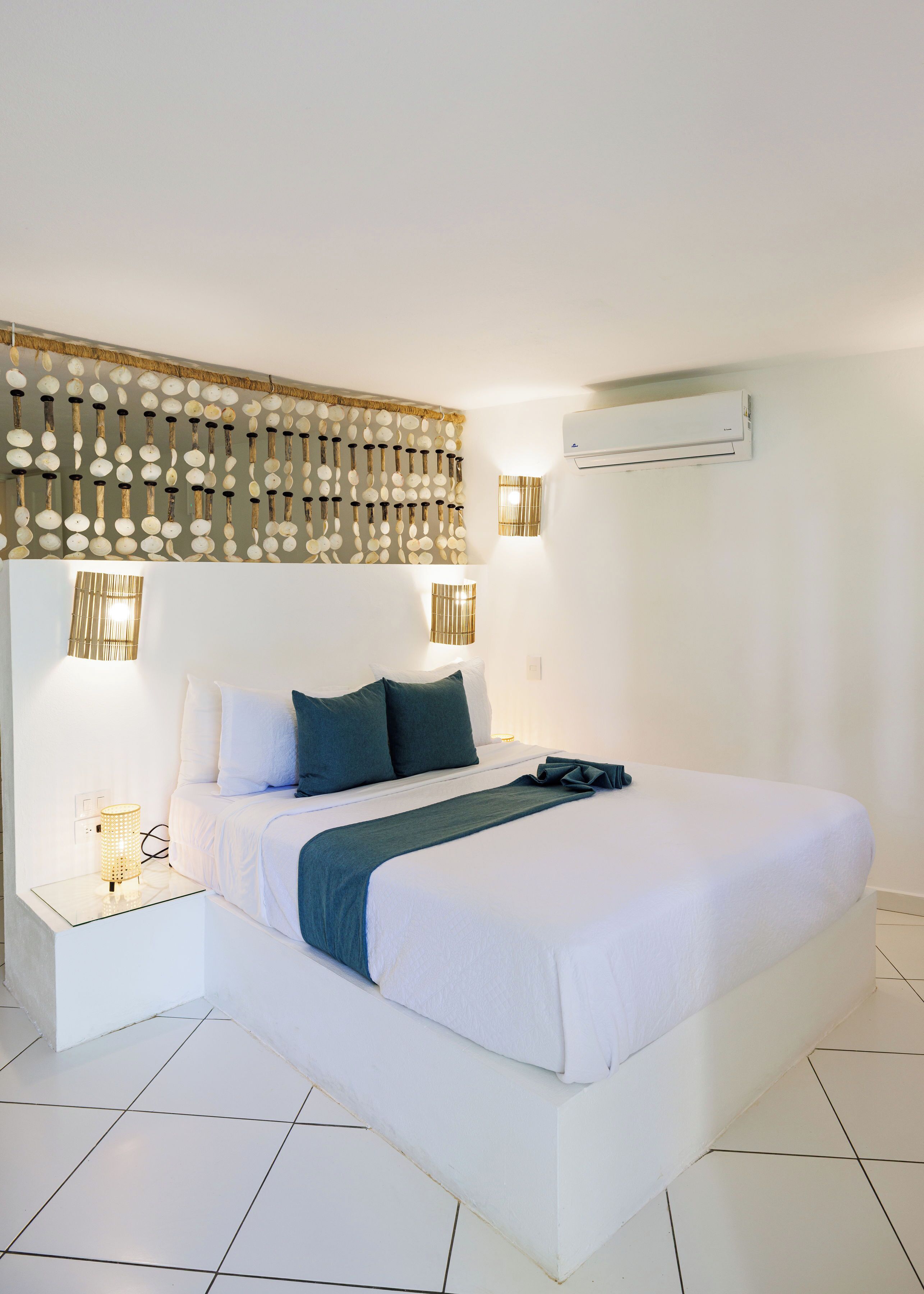 Una habitación de hotel moderna con una cama grande, lámparas de noche, un equipo de aire acondicionado y un panel decorativo en la pared.