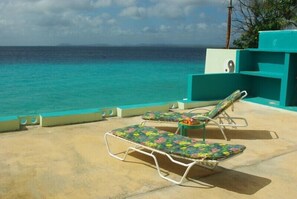 A poolside area with lounge chairs and a view of the ocean. - Villa Sunset Marina (Kralendijk)