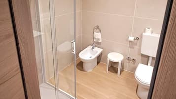 Ein modernes Badezimmer mit Glasdusche, Waschbecken, Toilette und Bidet.