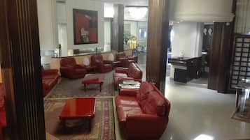 Eine Lobby mit roten Ledersofas, einem Couchtisch und einem gemusterten Teppich.