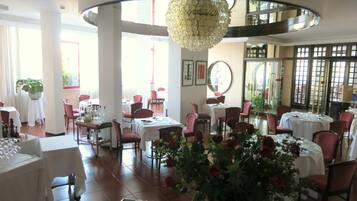 Ein Restaurantinneres mit runden Tischen, Stühlen und einer zentral platzierten Zierpflanze.